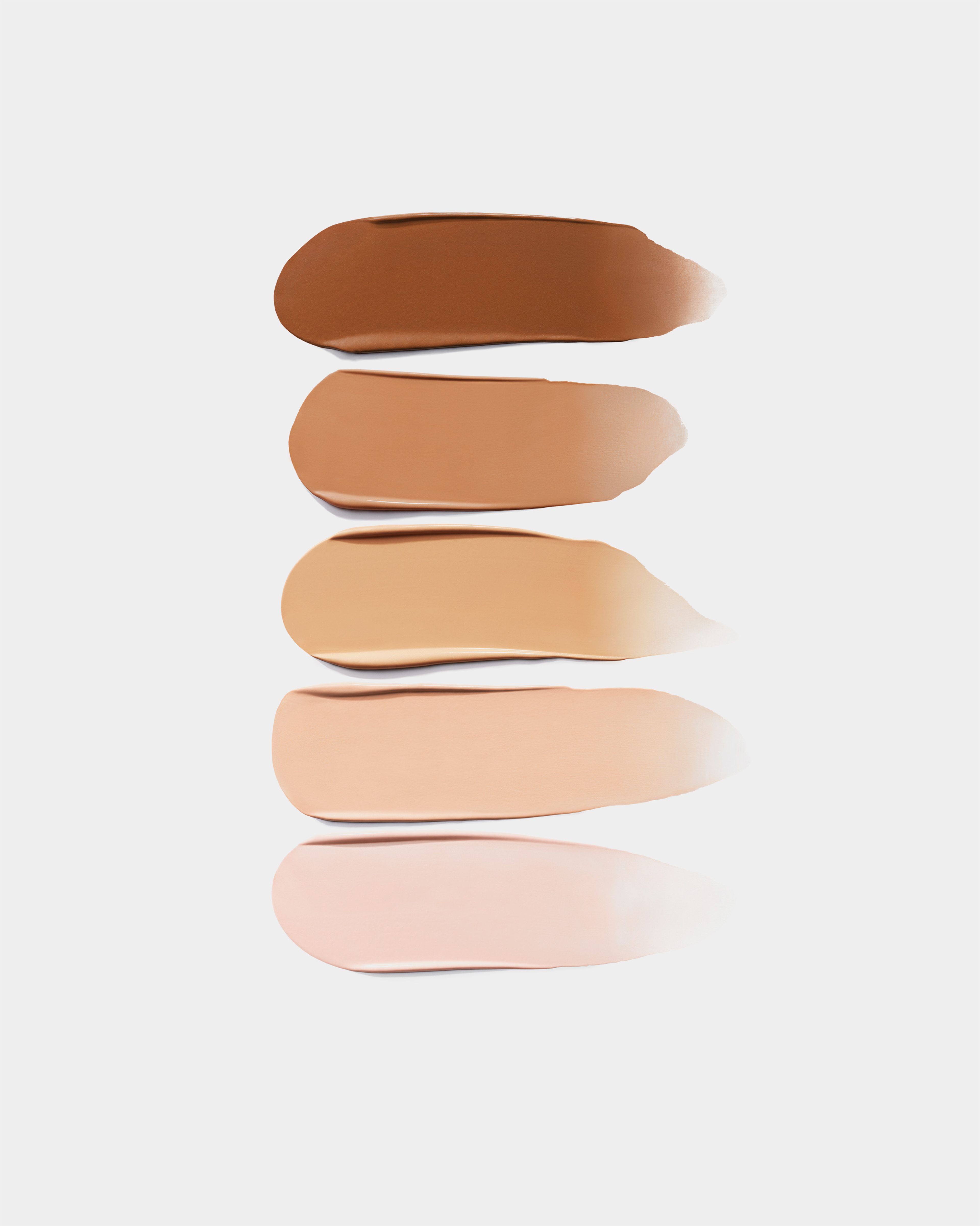 Swatches of tinted eye cream on a grey background