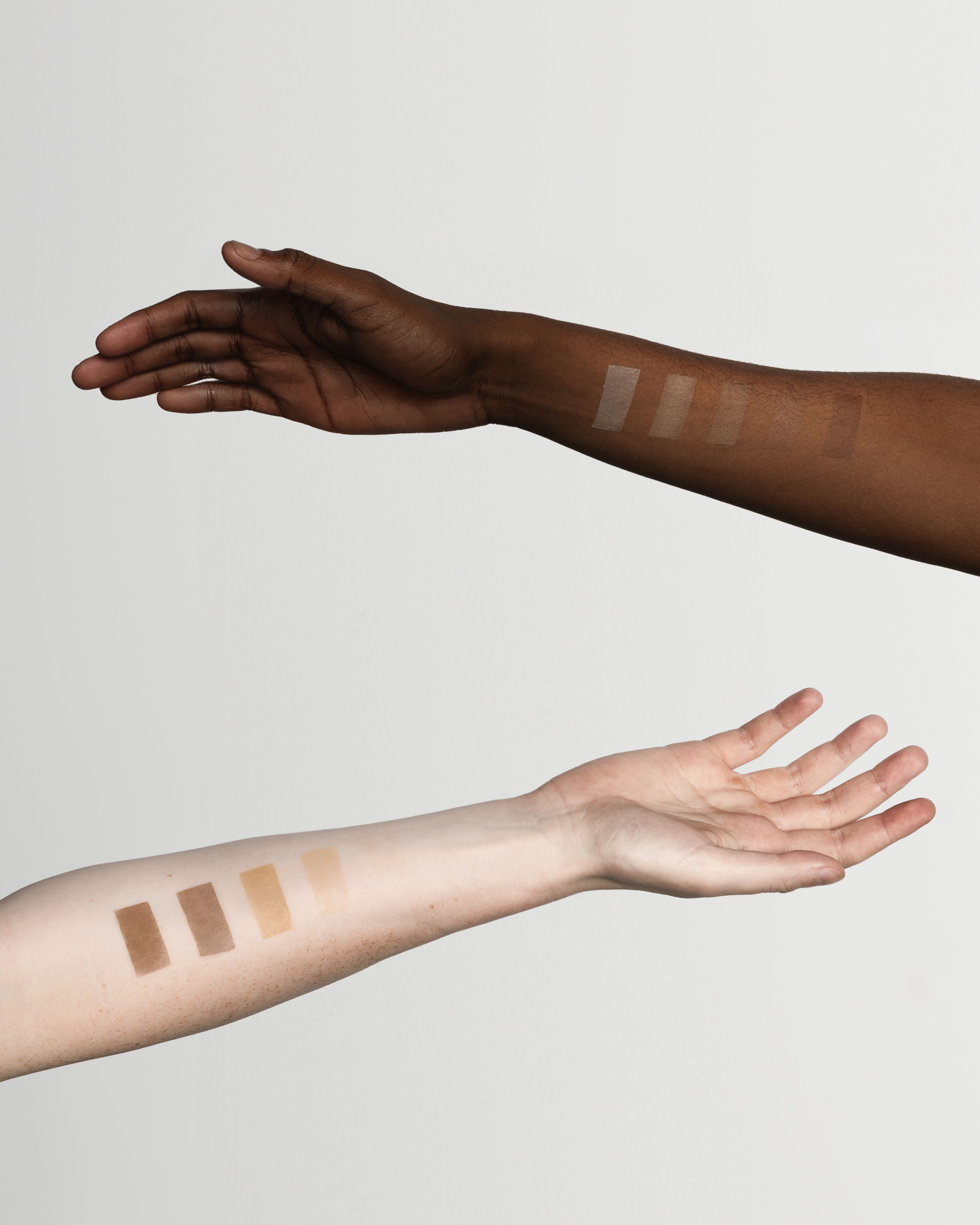 Two arms with swatches of a tinted moisturizer on them.