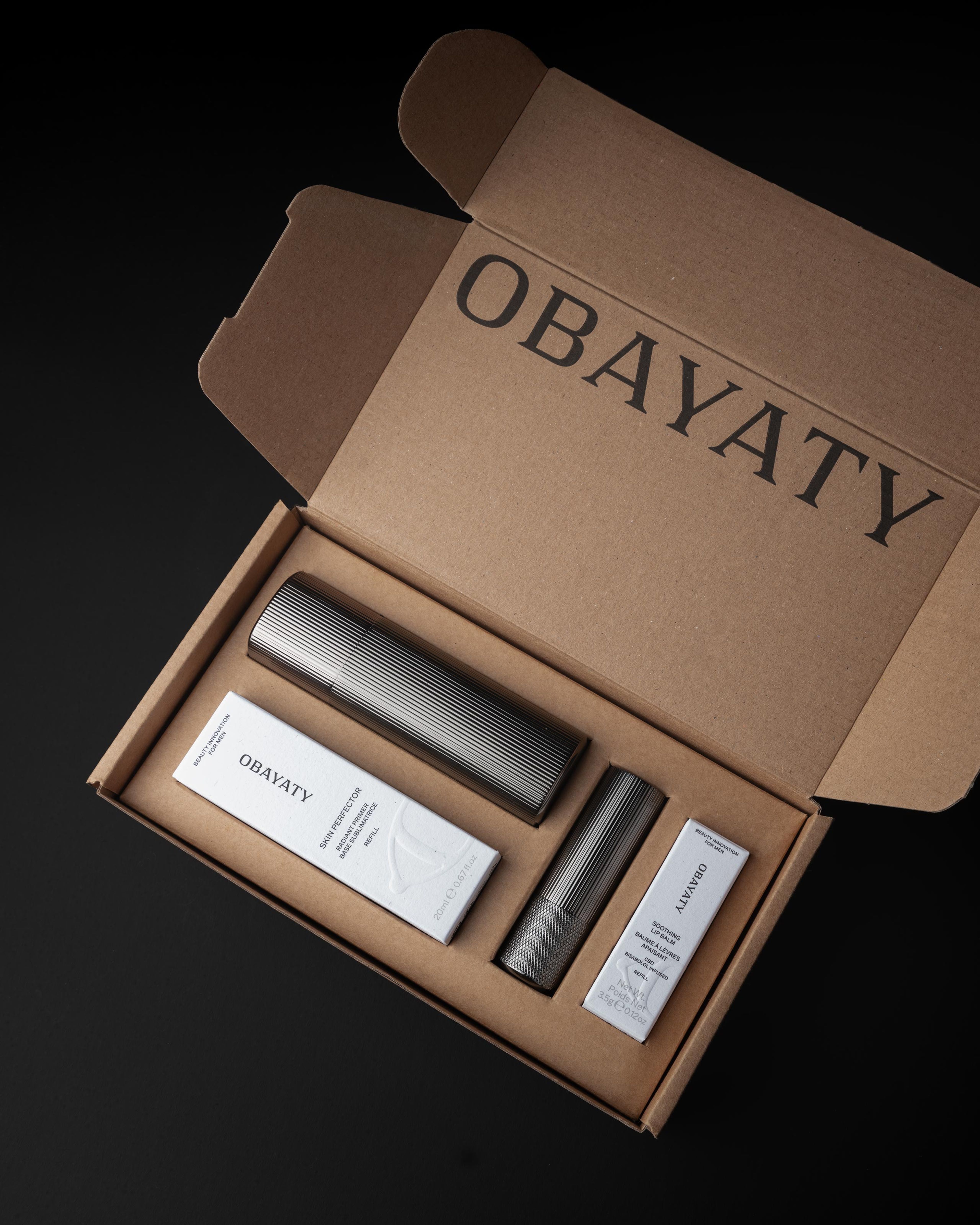 A men's moisturizer and lip balm laying In a cardboard gift box.