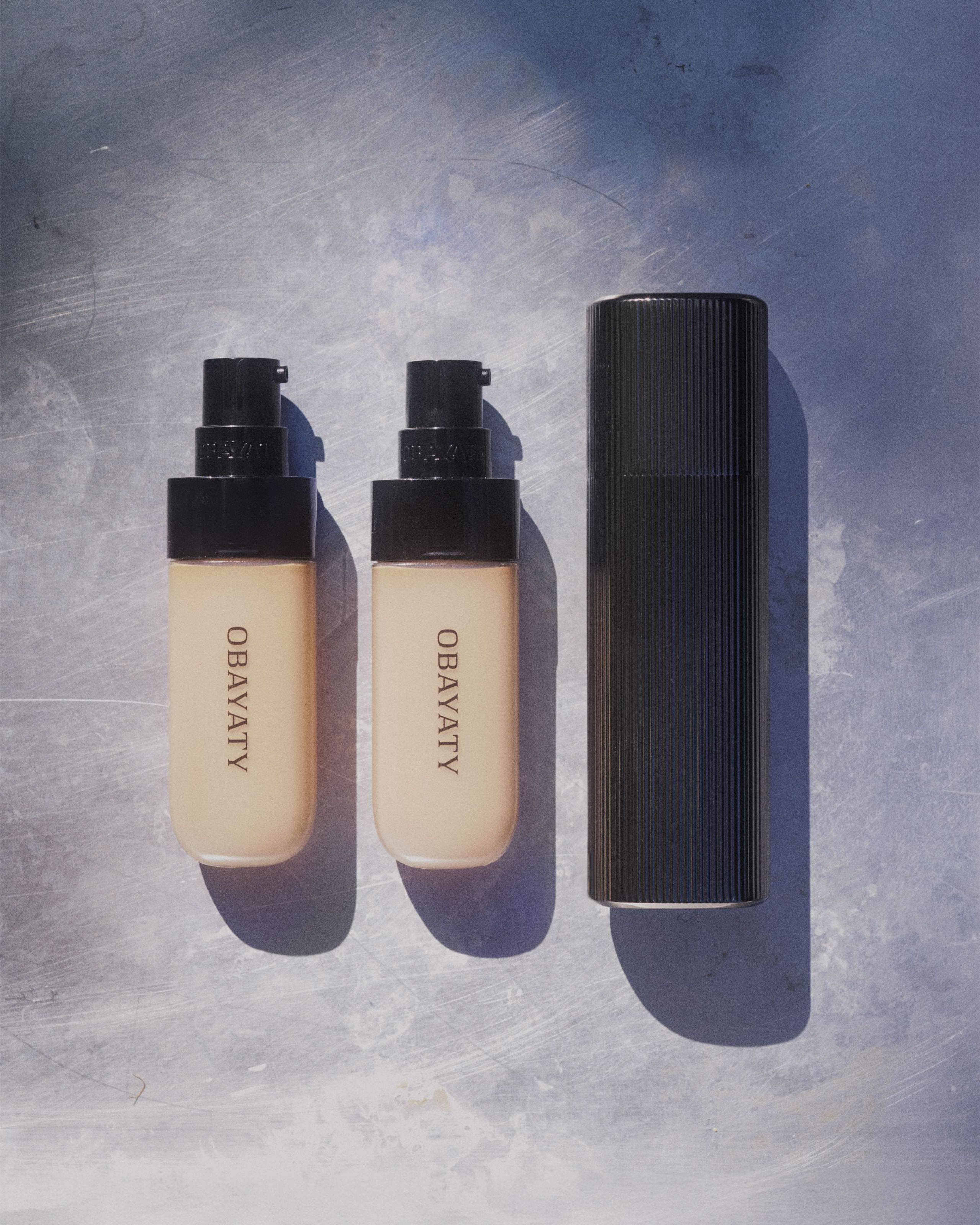 Tinted moisturizer metal case with two refills laying on a metal surface