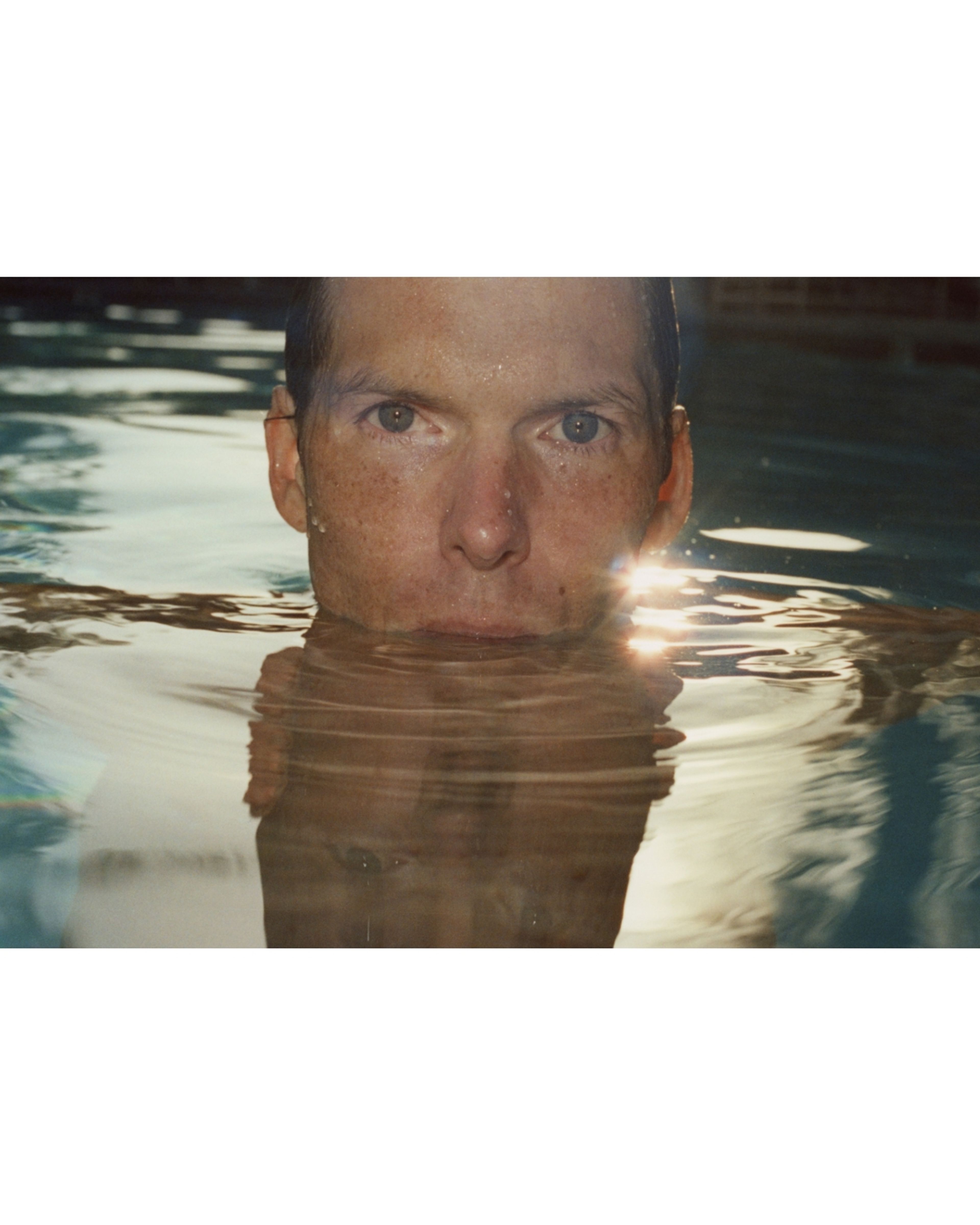 A man swimming in a pool at sunset