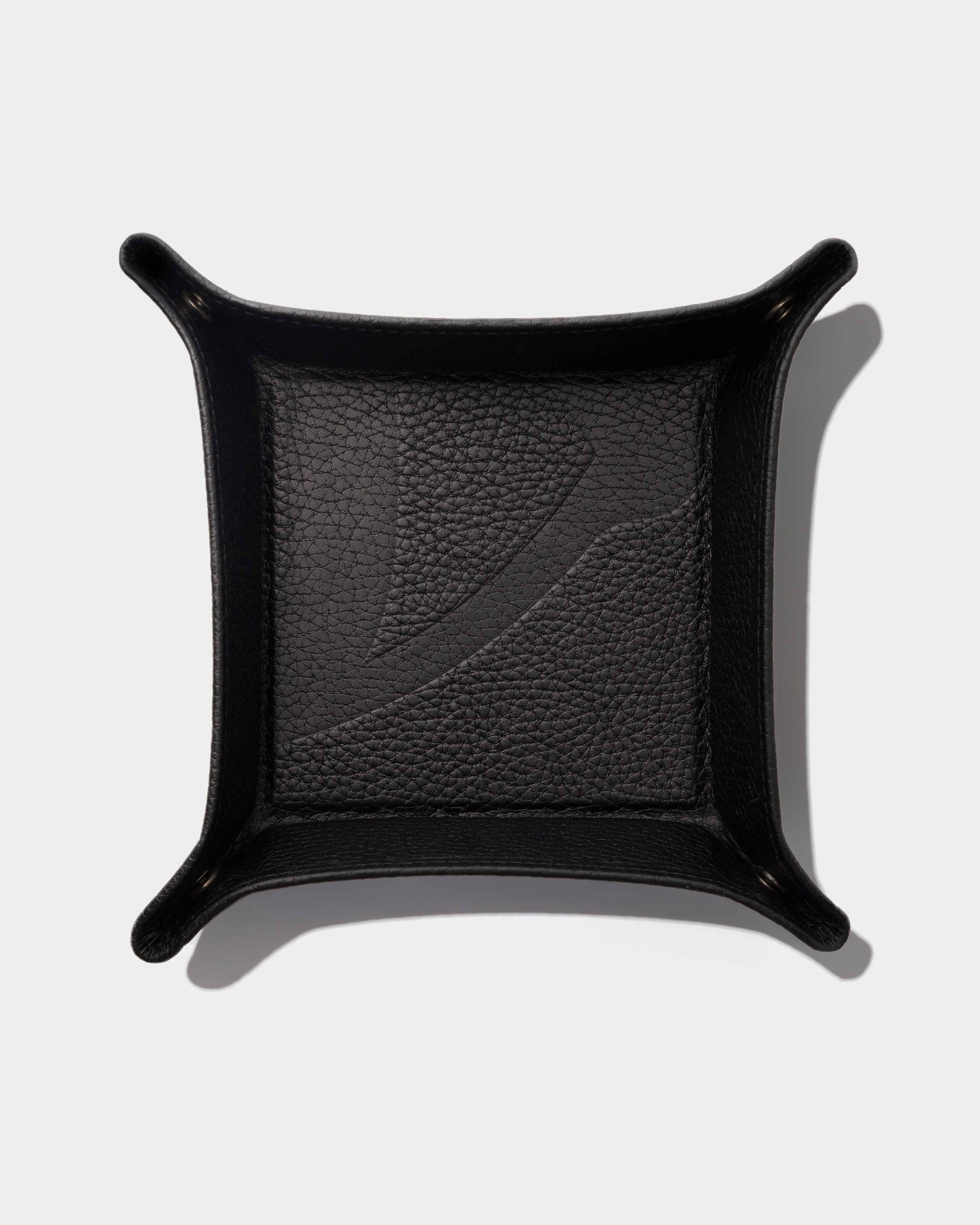 Black leather tray laying on a grey background