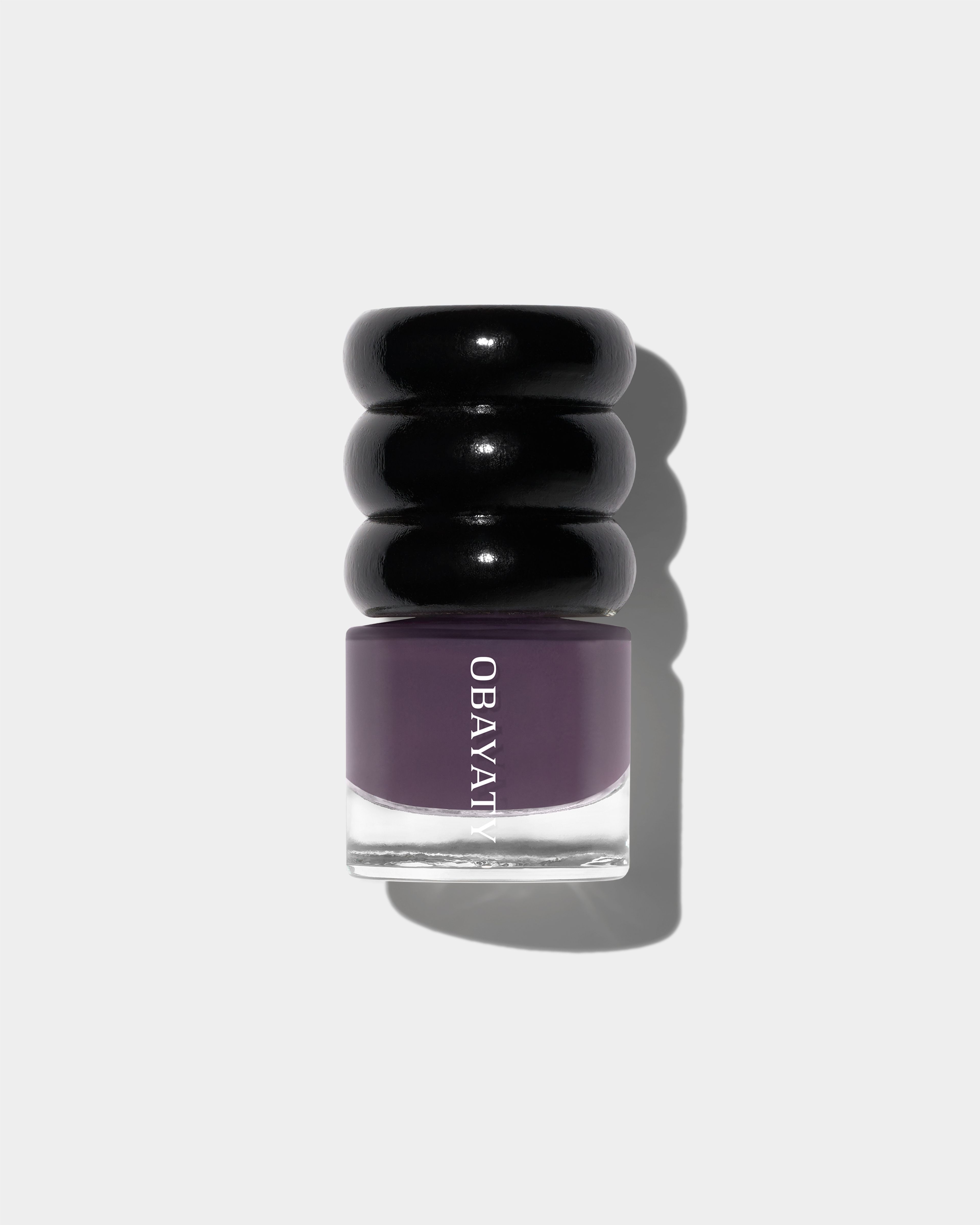Nail polish in the color violet dusk laying on a grey surface