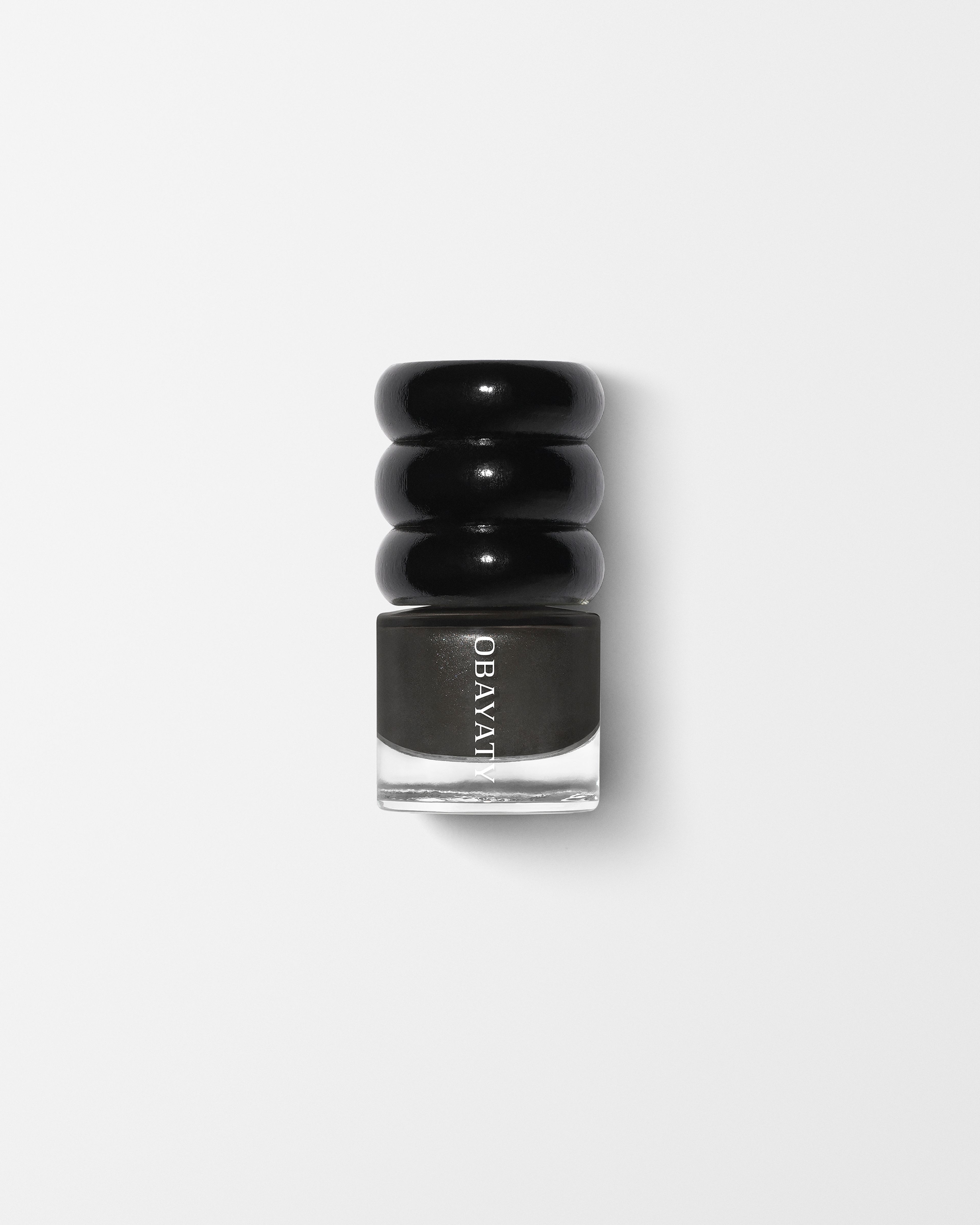 Black wood cap and glass bottle of nail polish in the color off black laying on a grey surface