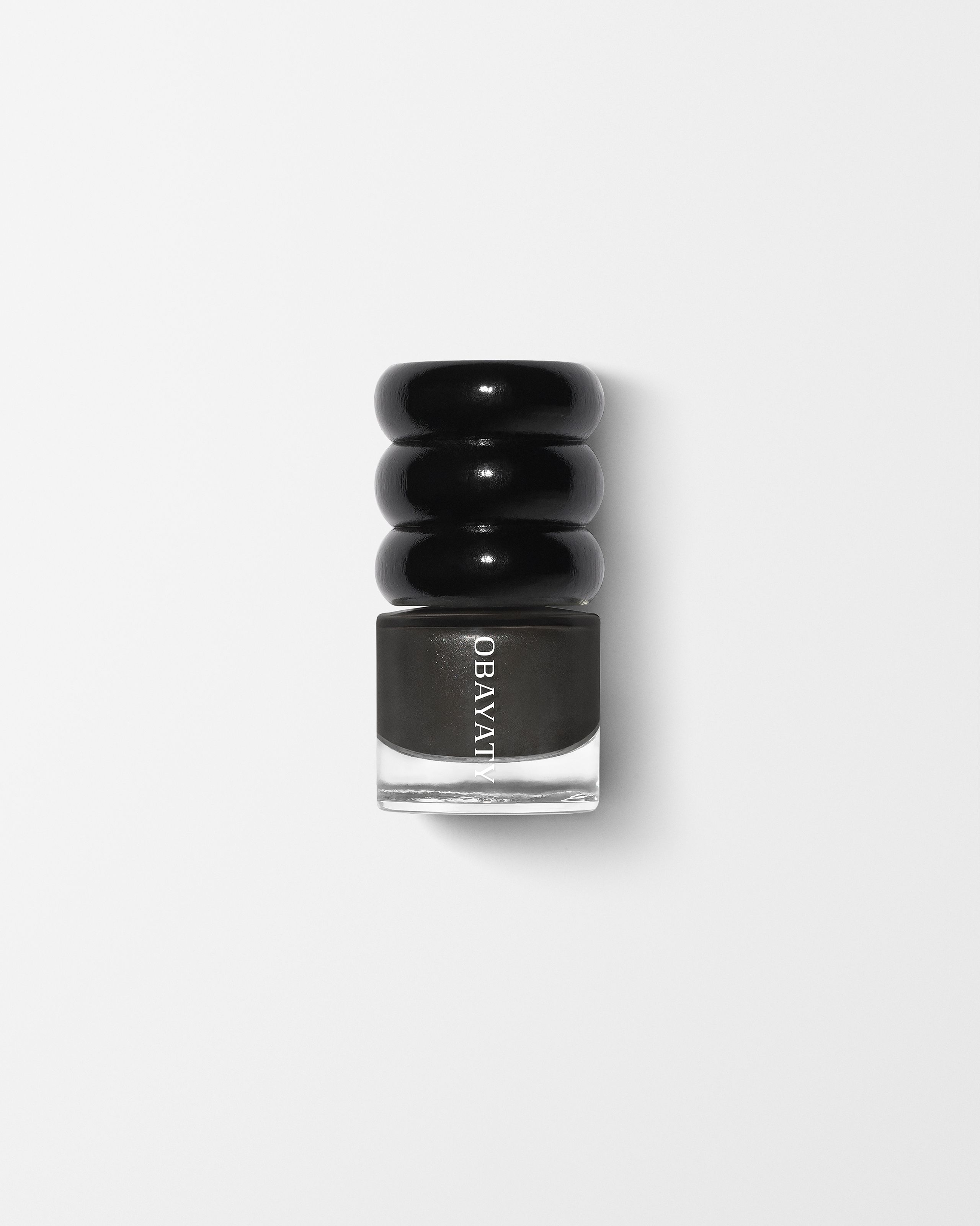 Black wood cap and glass bottle of nail polish in the color off black laying on a grey surface