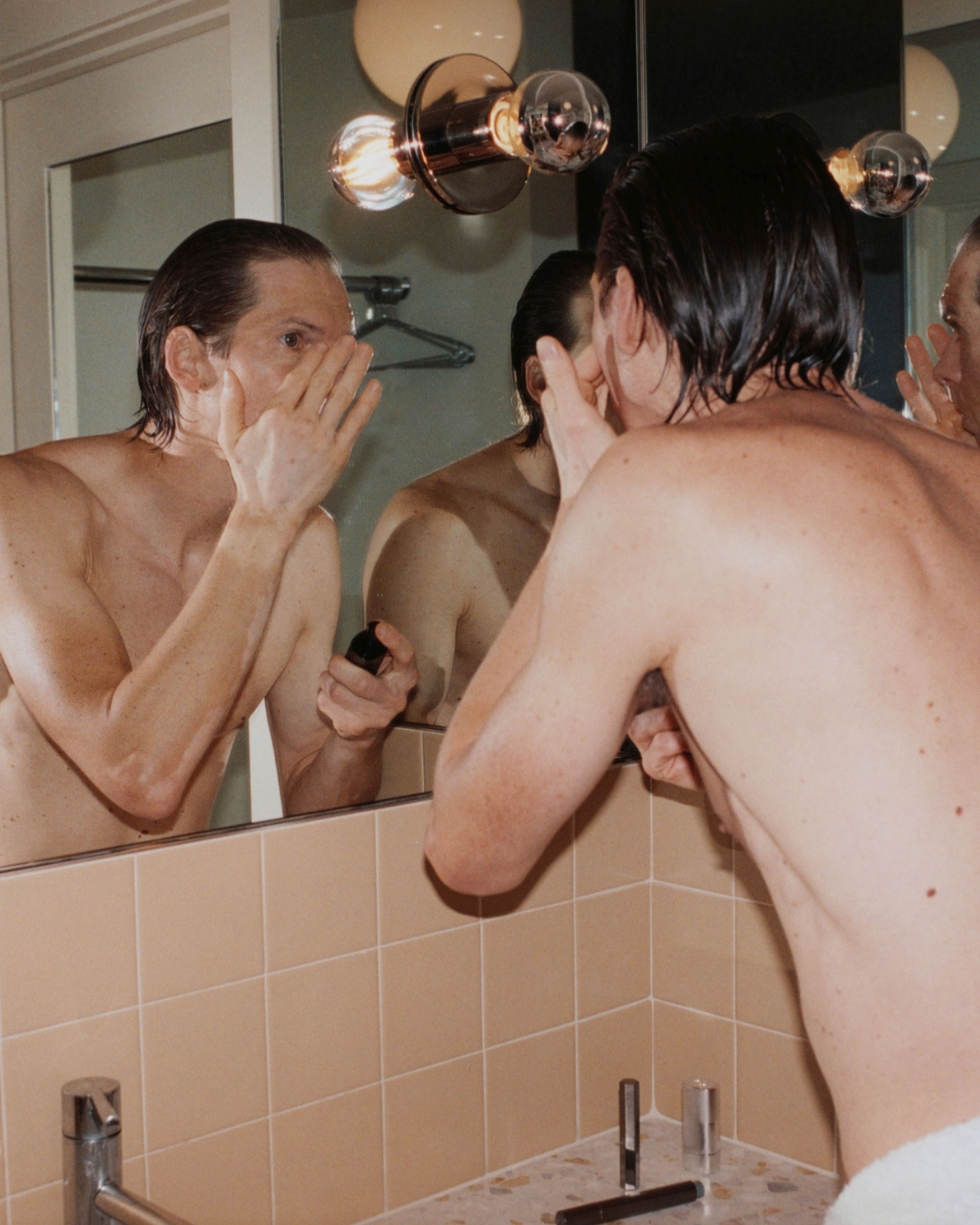A man standing in front of a mirror applying moisturizer