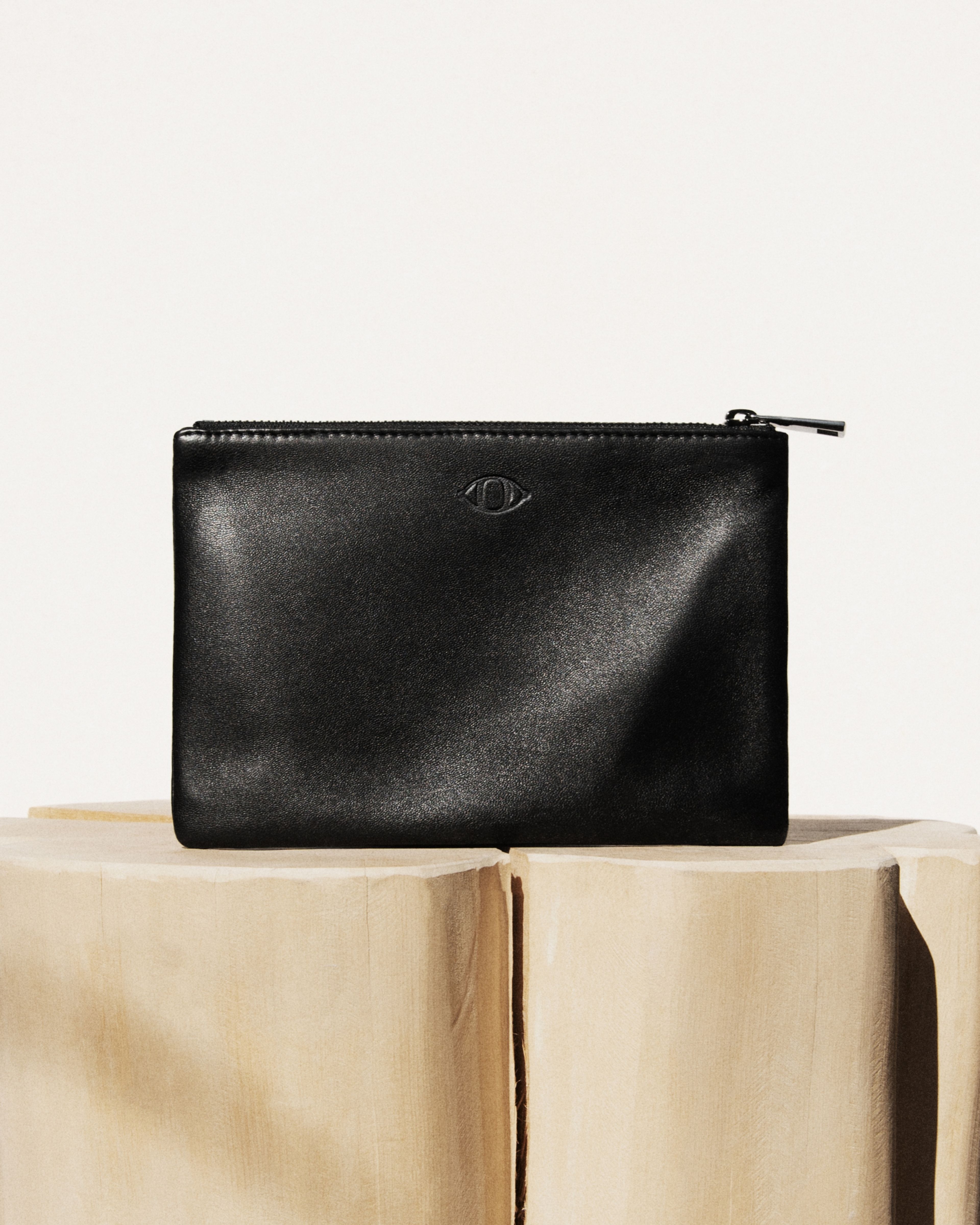 Black leather pouch laying on grey background