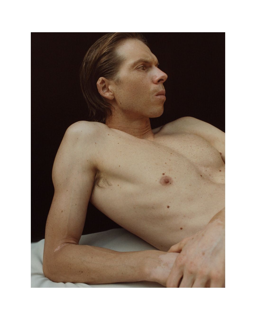 A man laying on a surface looking away from the camera