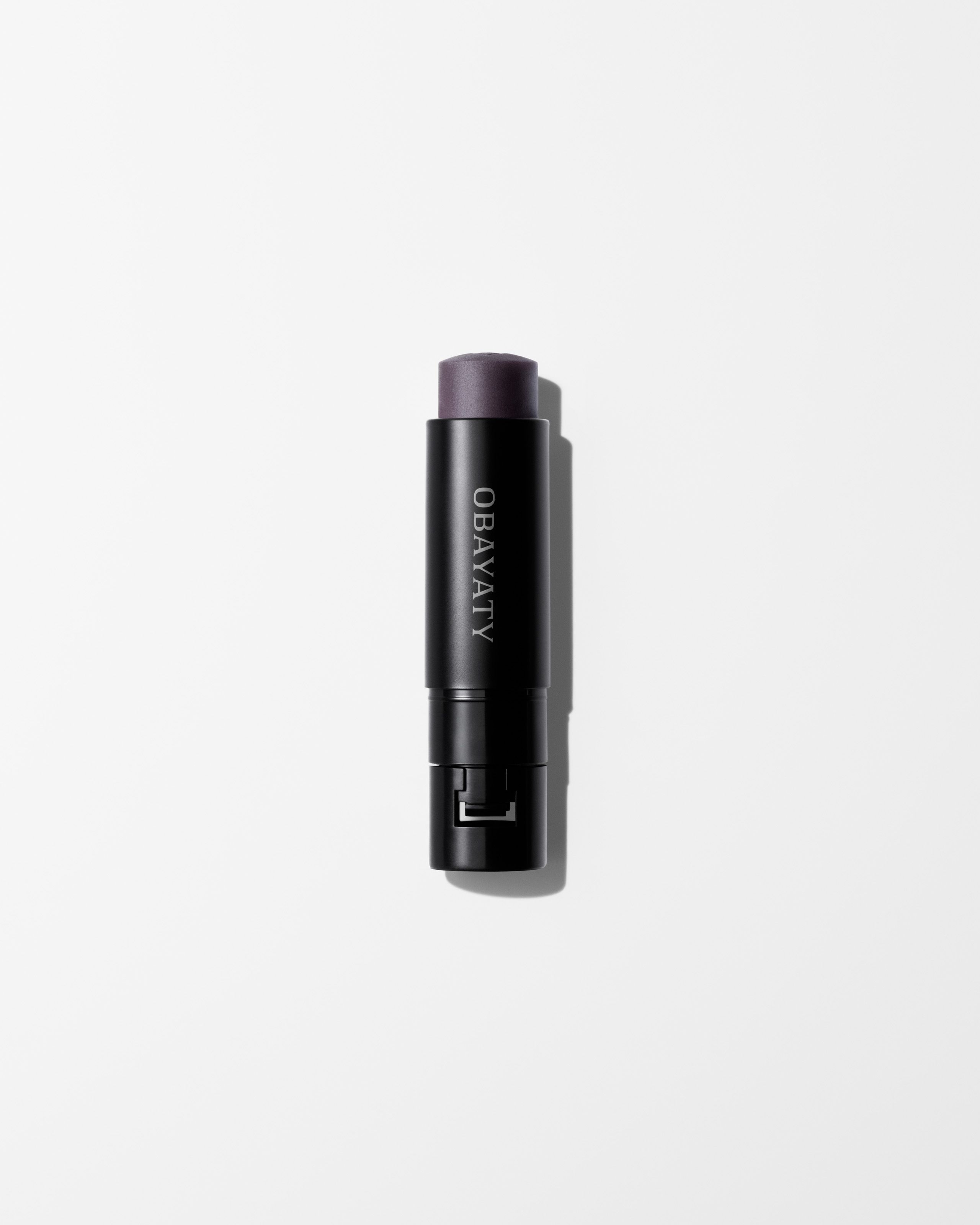 Enhancing Lip Balm refill laying on a grey background.