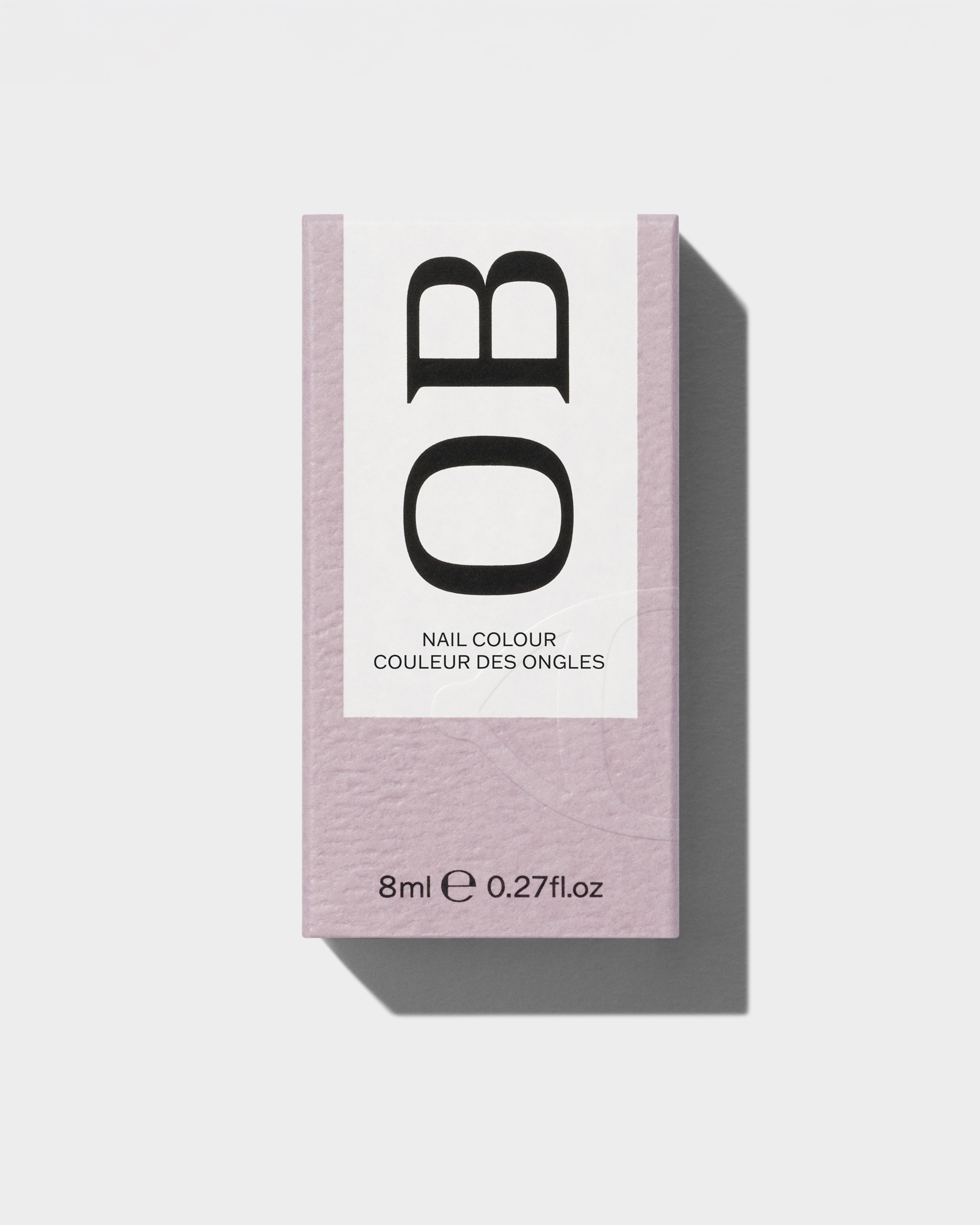 Nail polish packaging laying on a grey surface