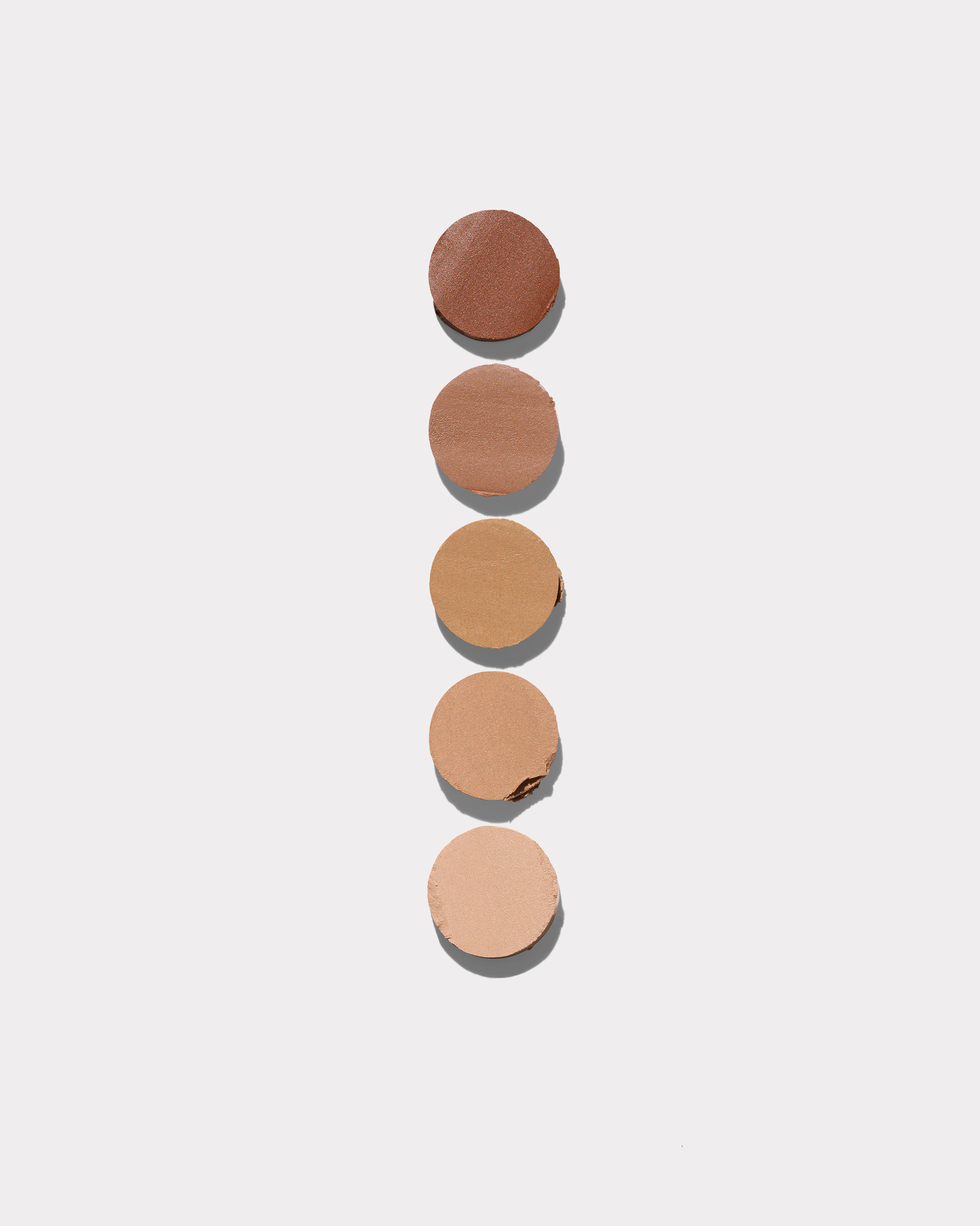 Concealer formula swatches laying on a grey background