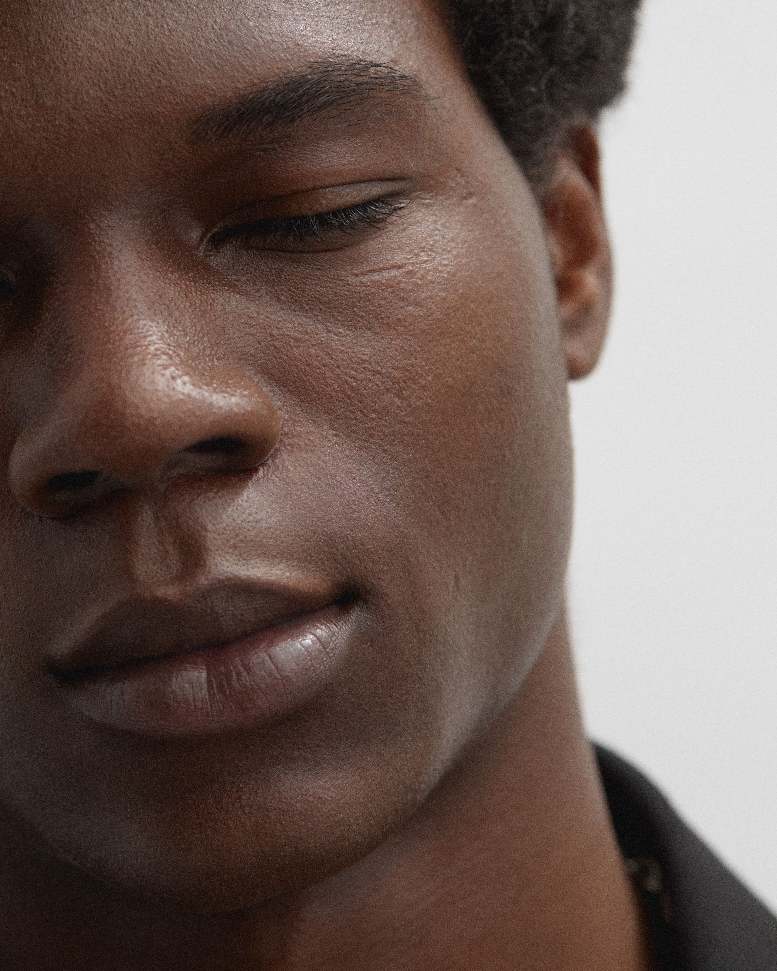 Man with closed eyes in front of a grey background