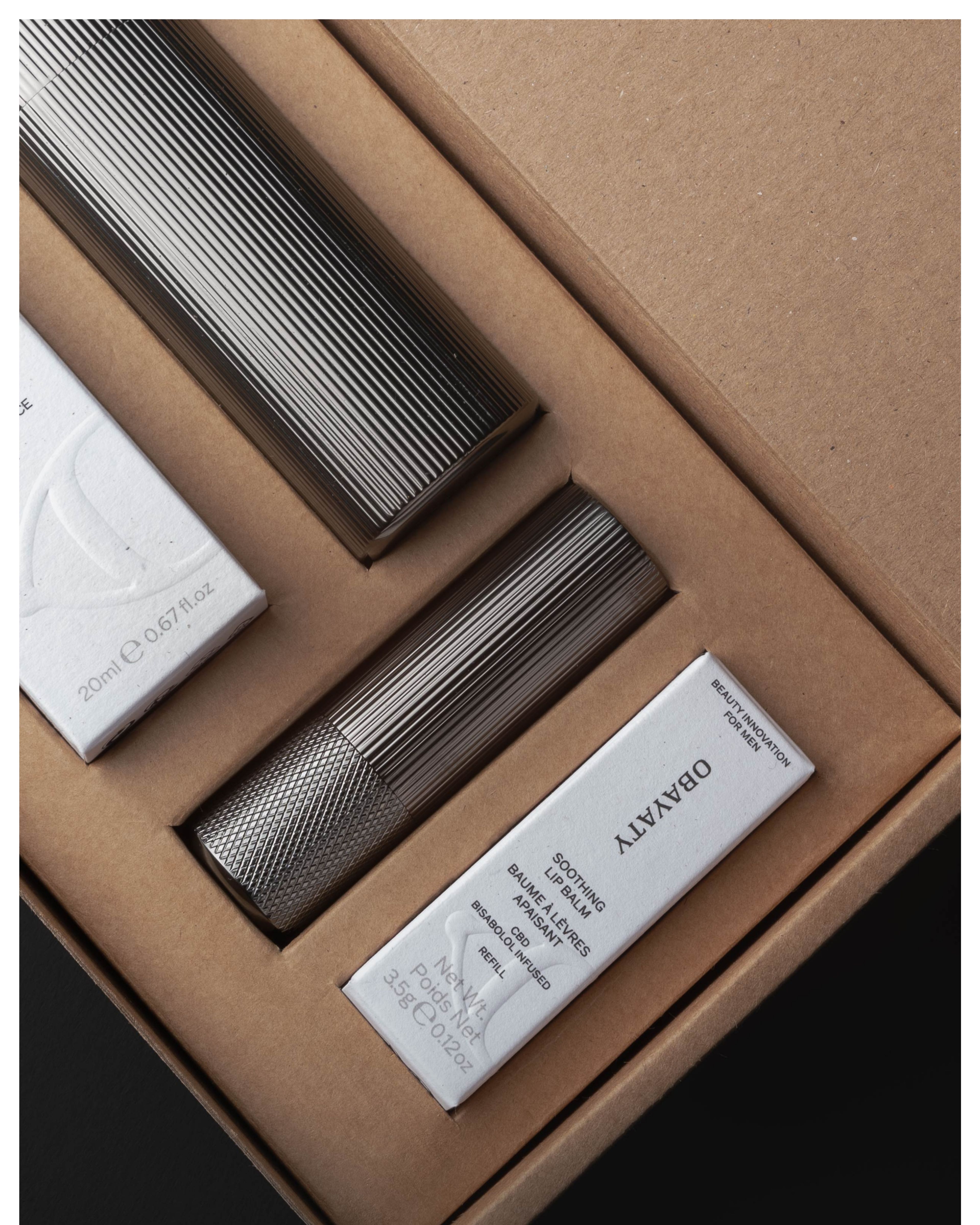 A kit containing a mens moisturizer and lip balm. Laying in a cardboard box.