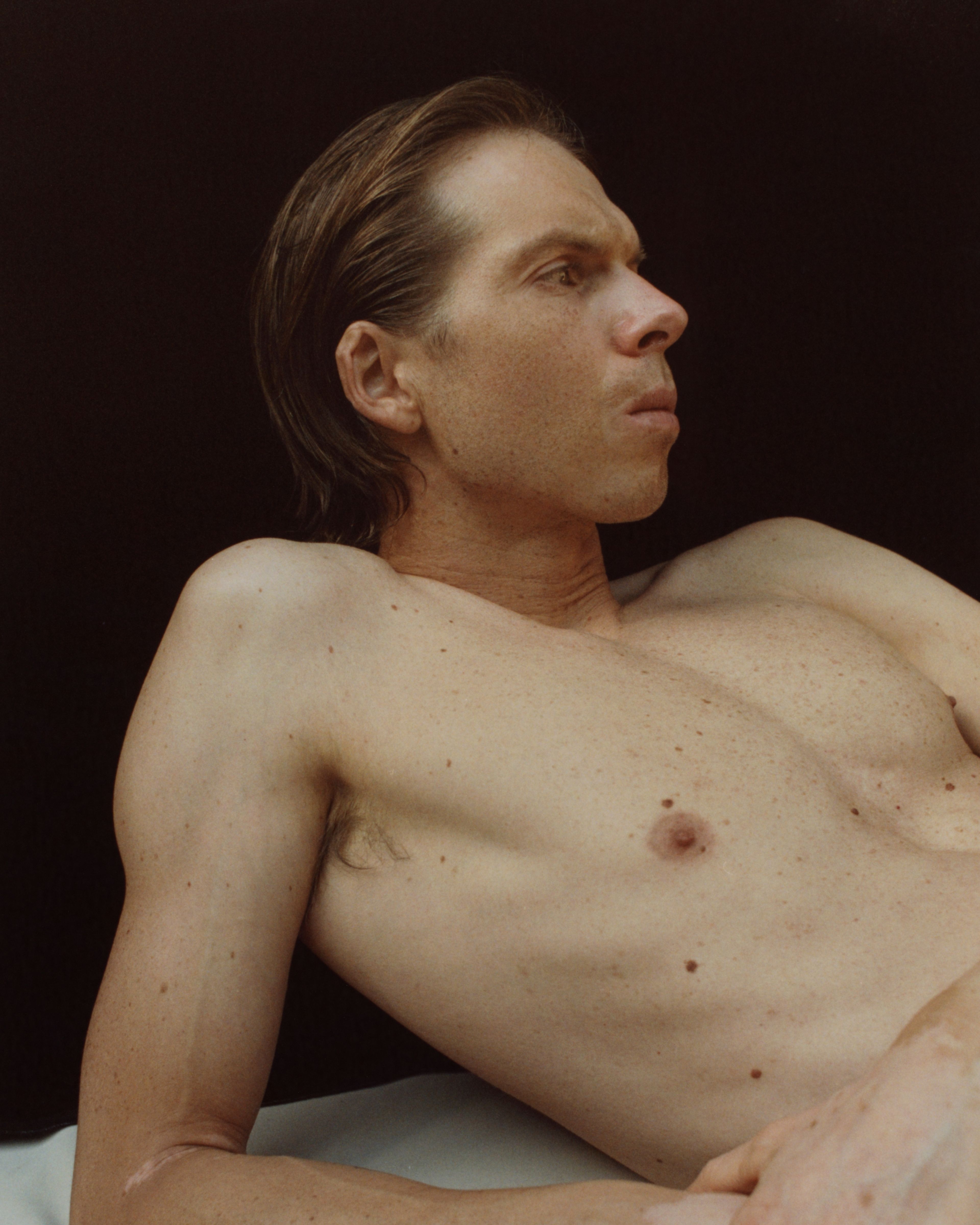 Man laying down infront of a black background